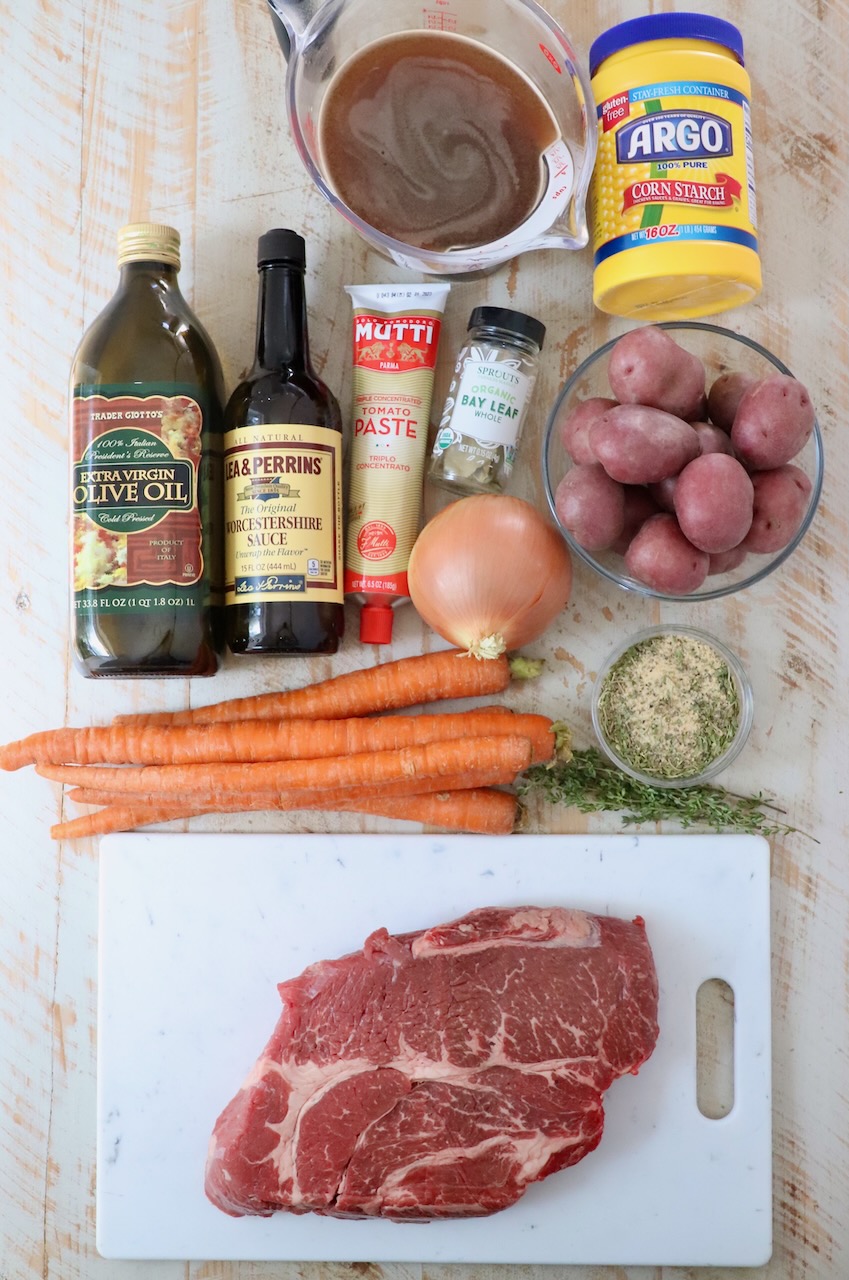 ingredients for pot roast on a white wood board