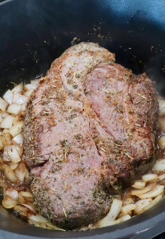 seared chuck roast in a dutch oven with onions