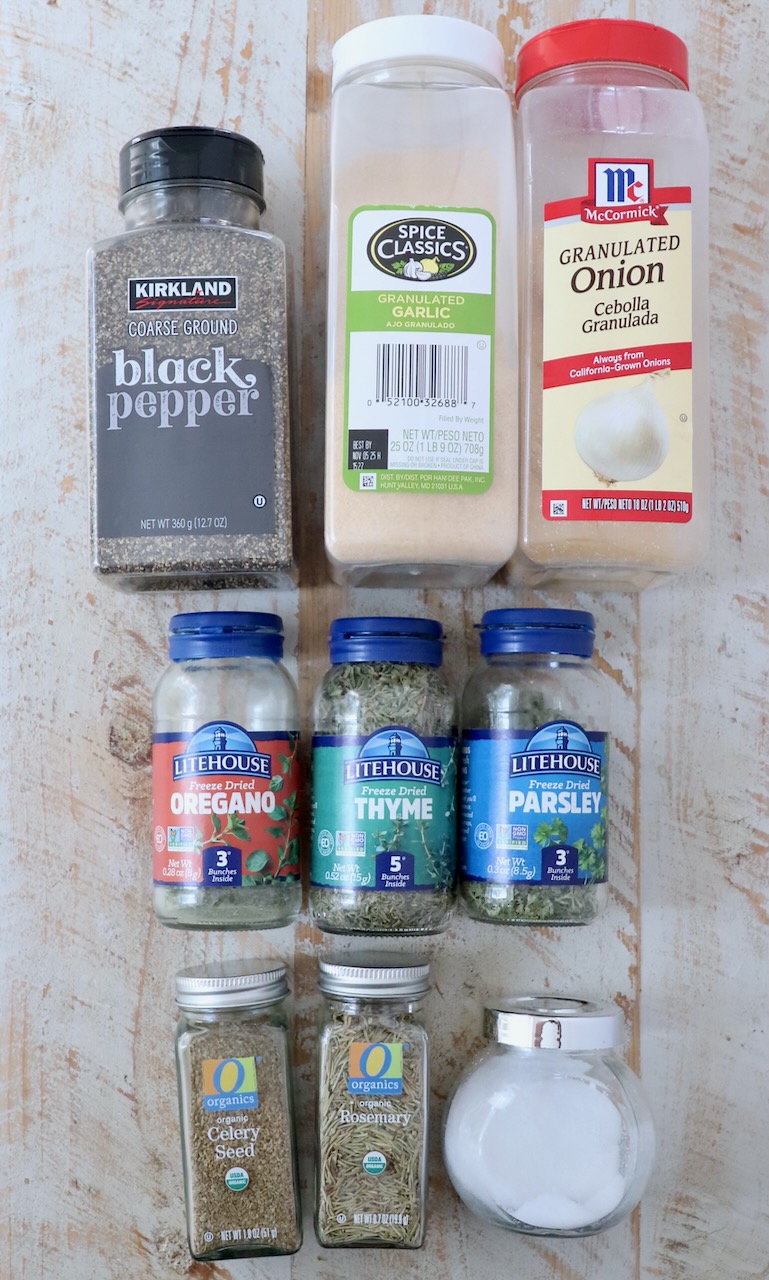 herbs and spices in jars on white wood board