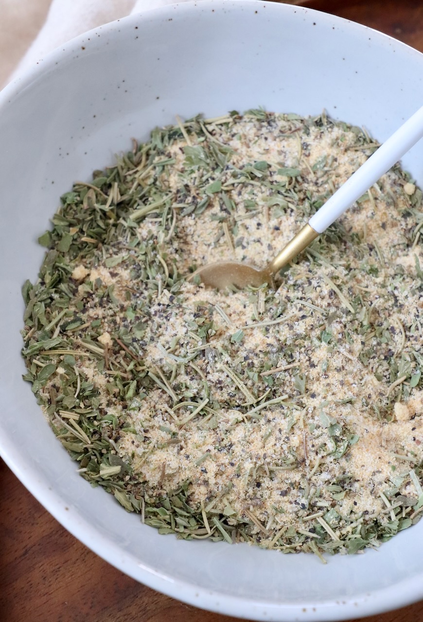 herbs and spices mixed together in a bowl with a spoon