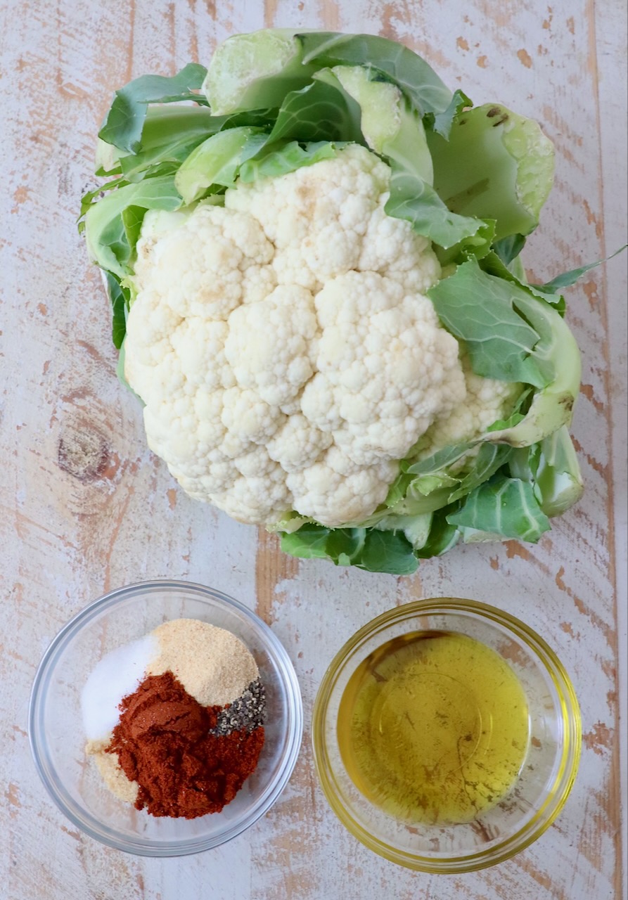 head of cauliflower next to small bowl of spices and small bowl of oil