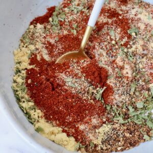 herbs and spices mixed together in a bowl with a spoon