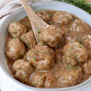 meatballs in gravy in a bowl with a spoon