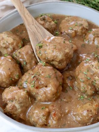 meatballs in gravy in a bowl with a spoon