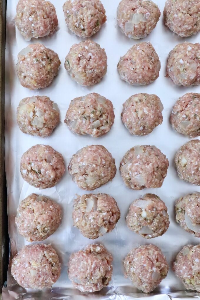 uncooked turkey meatballs on a foil lined baking sheet