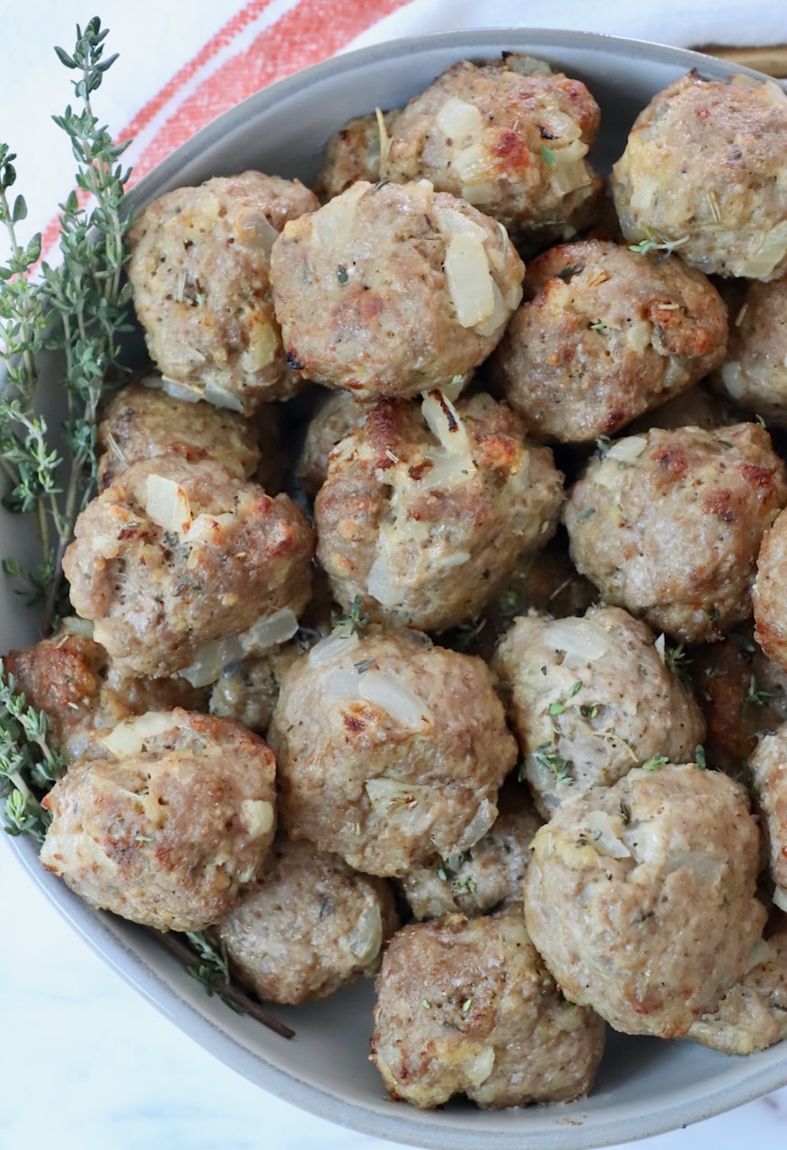 turkey meatballs stacked up in a bowl with fresh thyme