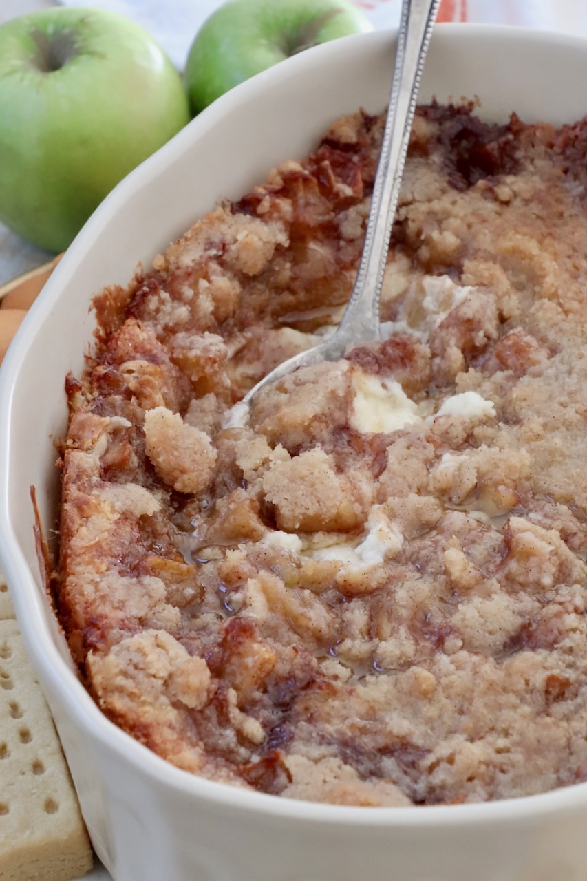 baked apple pie dip in a casserole dish with a serving spoon