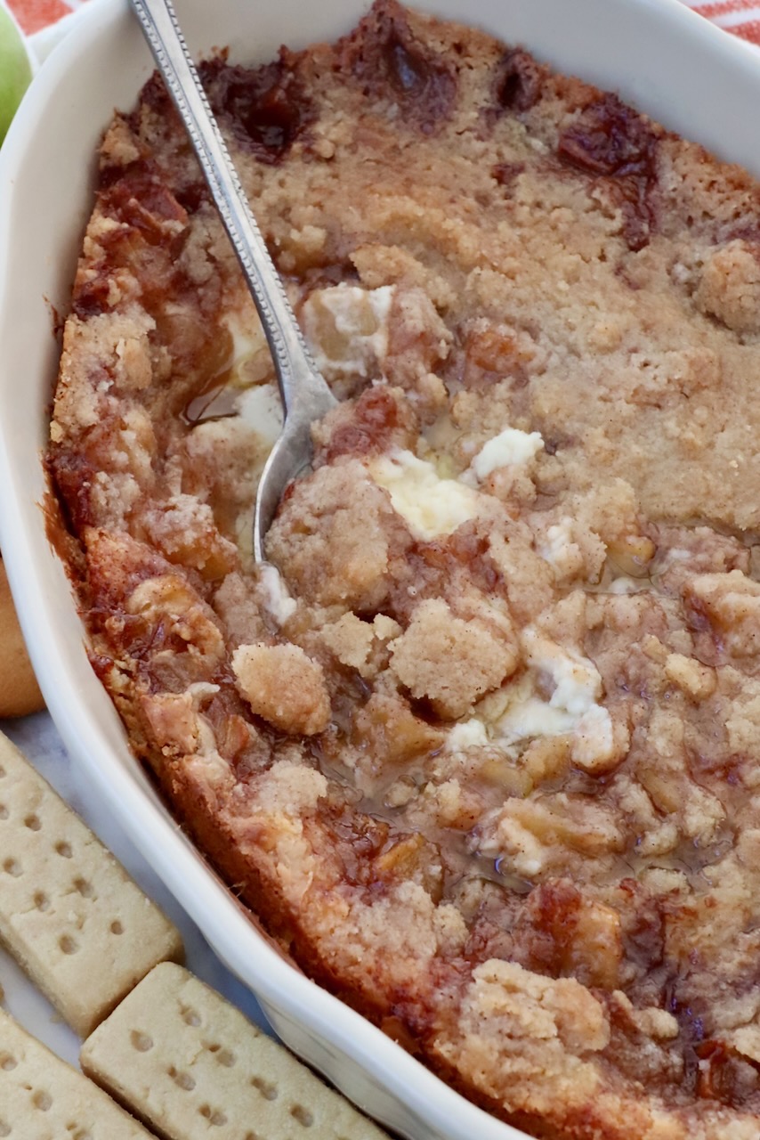 baked apple pie dip in a casserole dish with a serving spoon