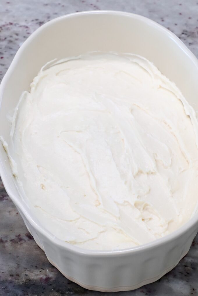 cream cheese filling spread in the bottom of a casserole dish