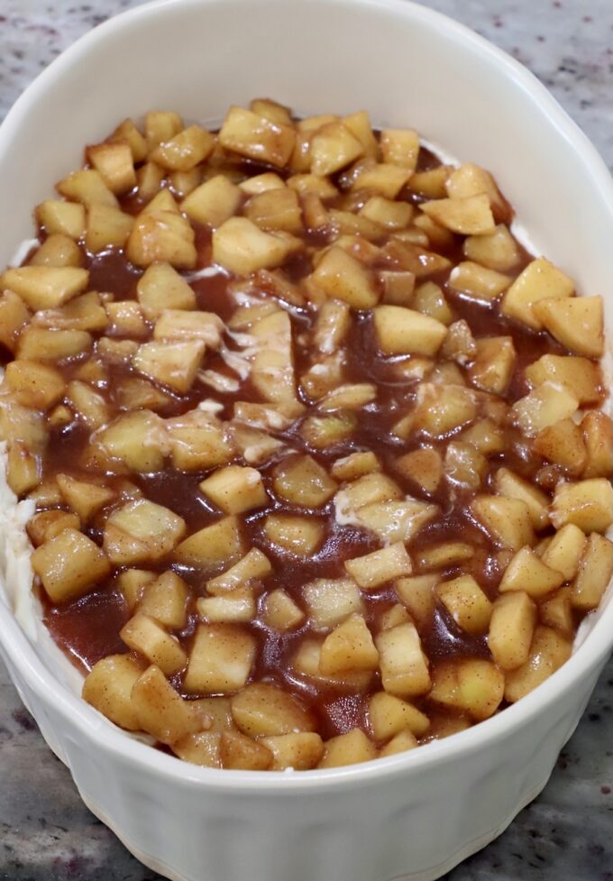 apple pie filling on top of cream cheese in a casserole dish