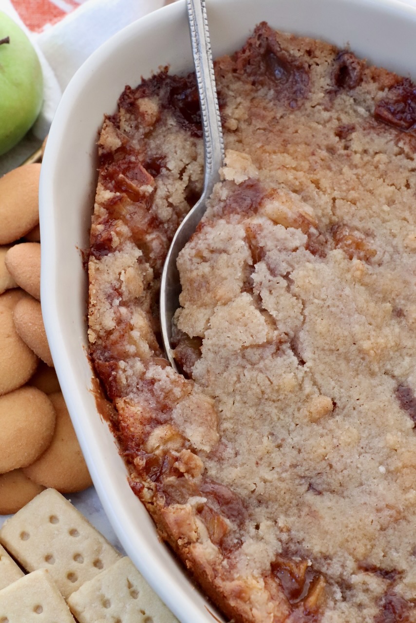 apple pie dip in a casserole dish with a serving spoon