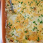 au gratin potatoes in a casserole dish with a serving spoon