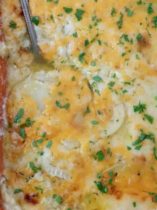 au gratin potatoes in a casserole dish with a serving spoon