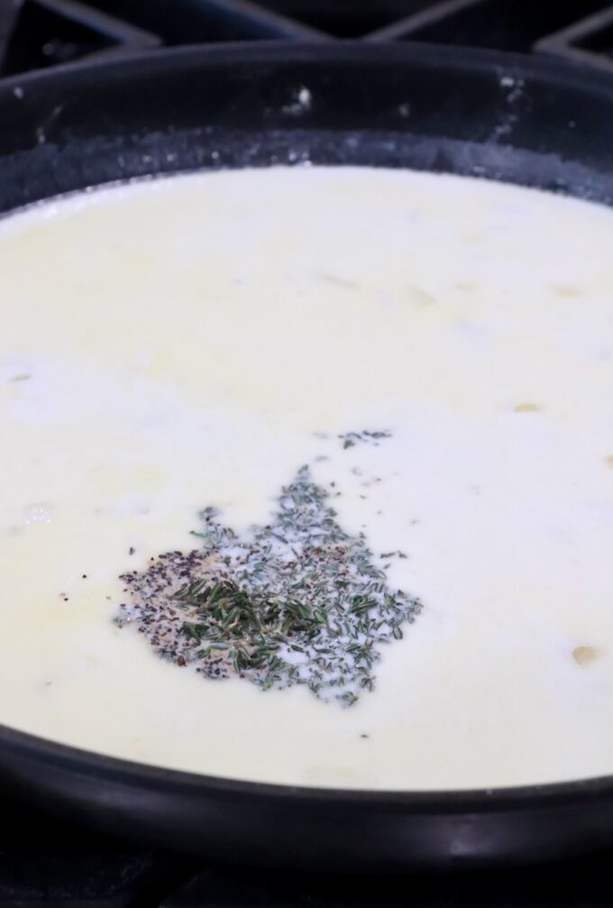 creamy sauce in a skillet with dried herbs and spices