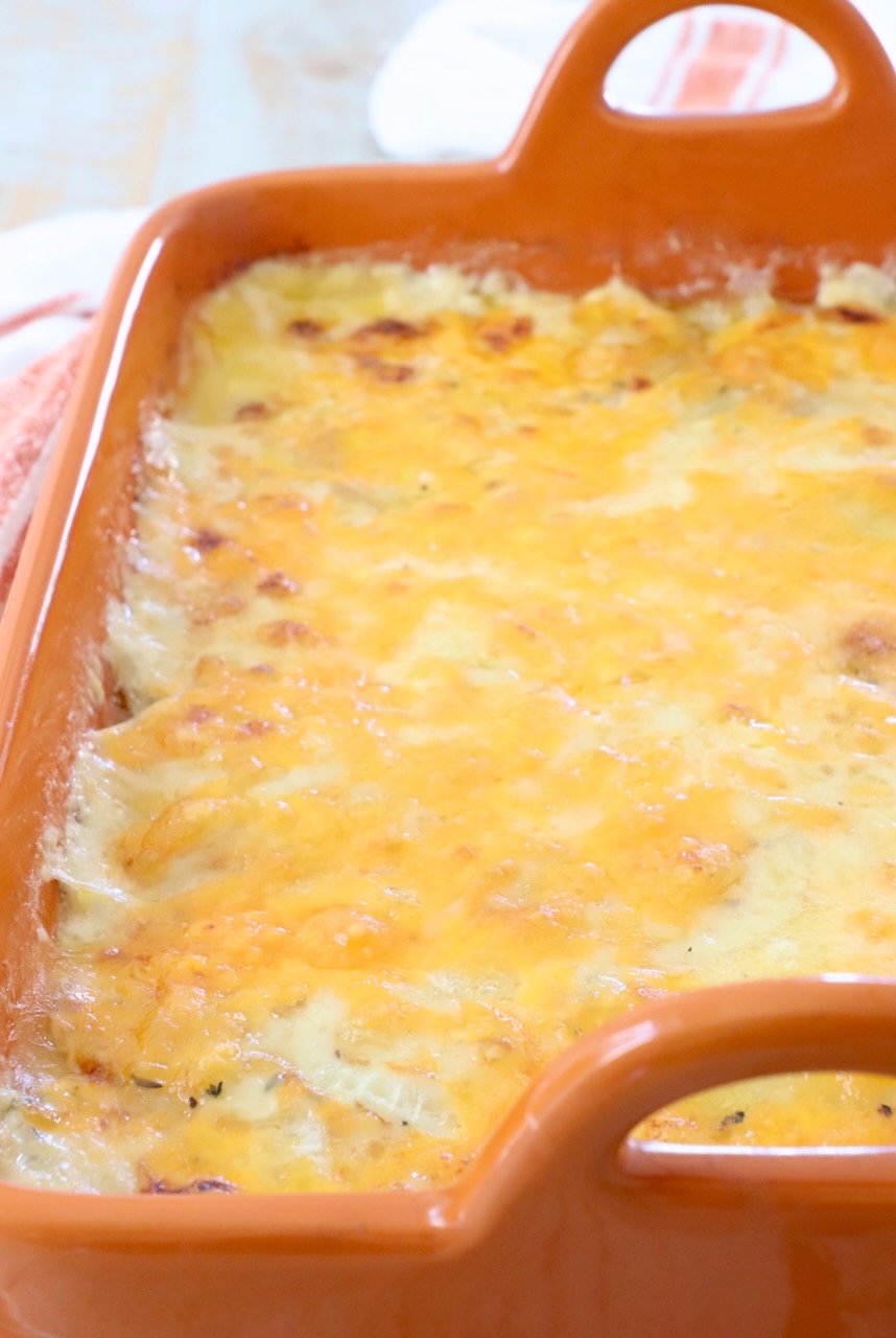 cheesy au gratin potatoes in an orange casserole dish