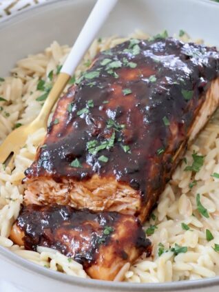 balsamic glazed salmon in a bowl with cooked orzo and a fork