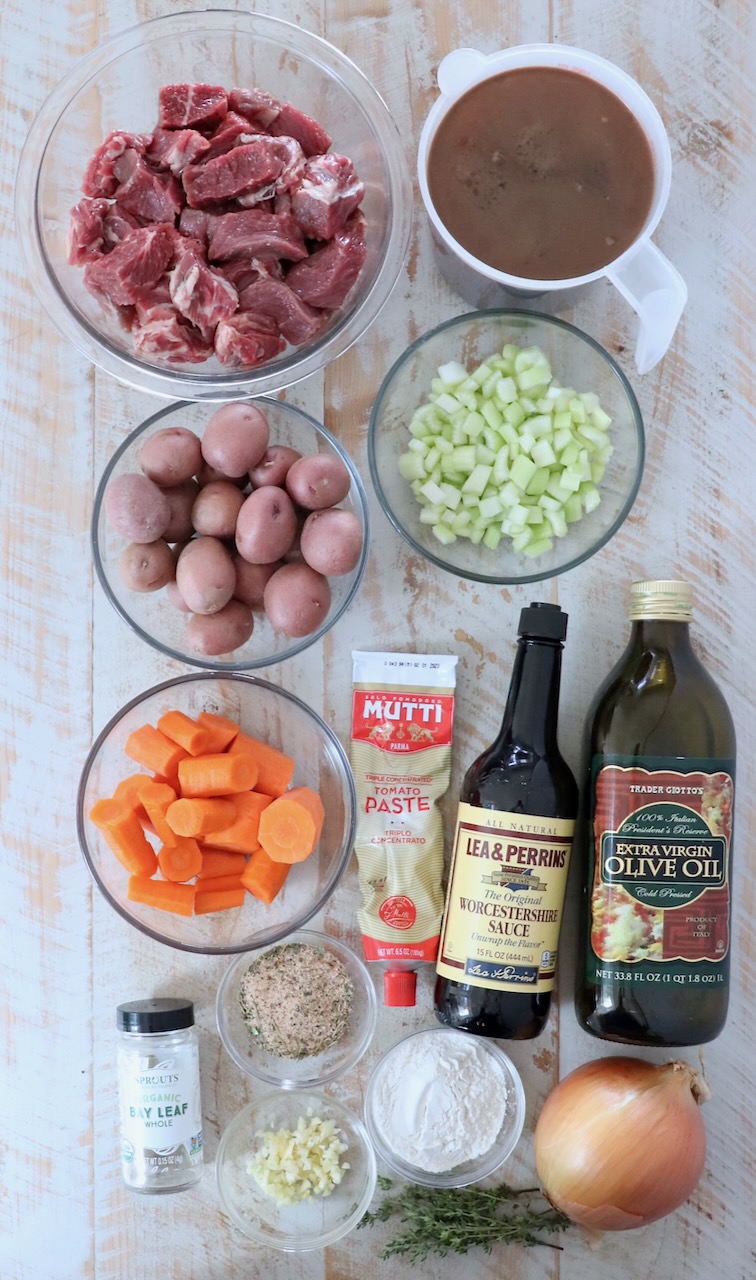 ingredients in beef stew on a white wood board