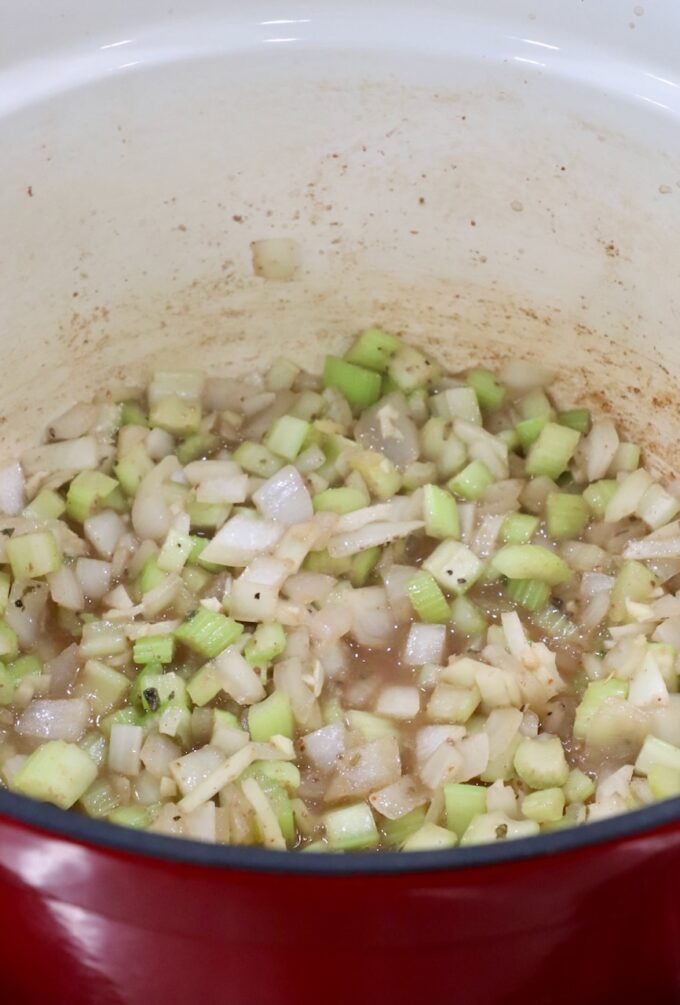 diced onions and celery in a dutch oven with broth