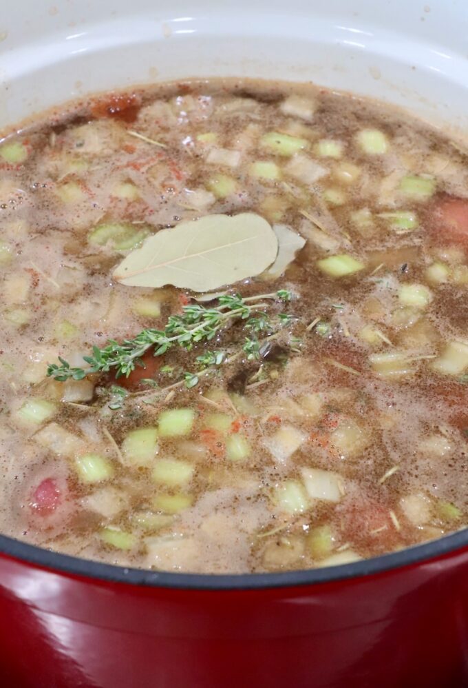 beef stew in a large dutch oven topped with bay leaves and thyme sprigs