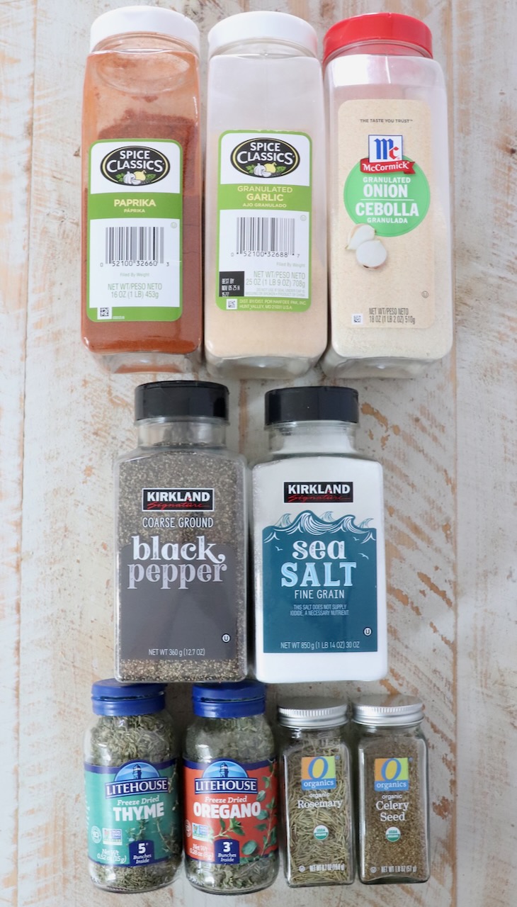 dried herbs and spices in containers on a white wood board