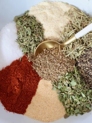 dried herbs and spices separated in a bowl with a spoon