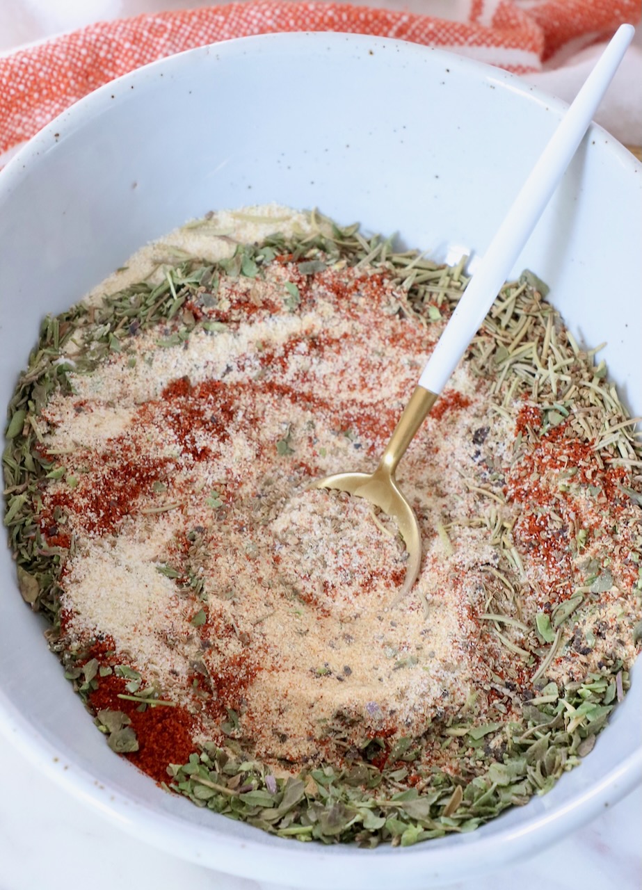 dried herbs and spices combined in a bowl with a spoon