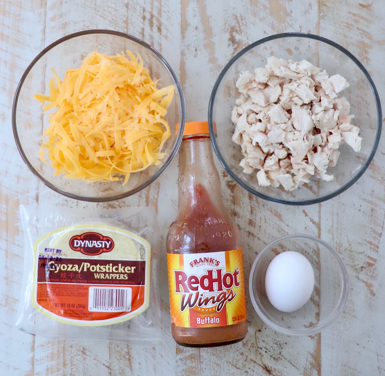 ingredients for buffalo chicken bites on a white wood board