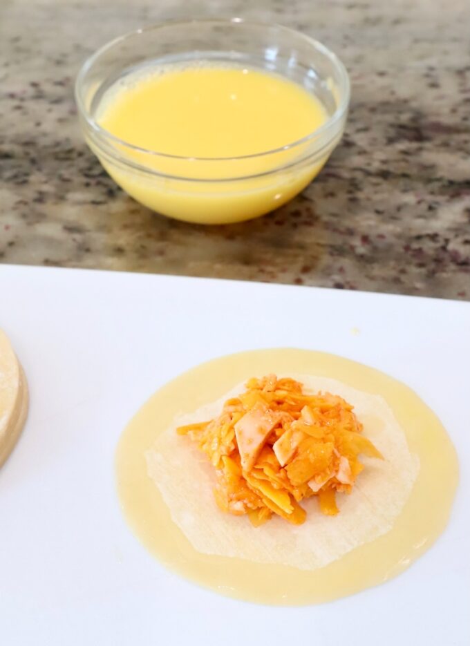 buffalo chicken in the middle of a gyoza wrapper on a cutting board