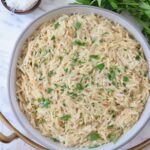 creamy orzo in a bowl topped with fresh chopped parsley