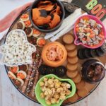 pretzels, popcorn, candies and cookies in small bowls on a wood board