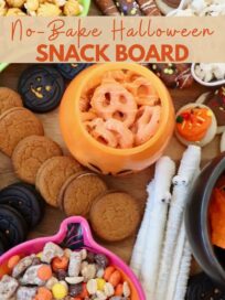 snack board with Halloween themed bowls of pretzels, candies and popcorn