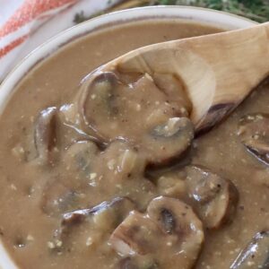 mushroom gravy in a bowl with a wooden spoon