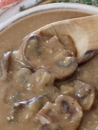 mushroom gravy in a bowl with a wooden spoon