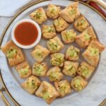 puff pastry pickles bites on a plate with a small bowl of hot sauce