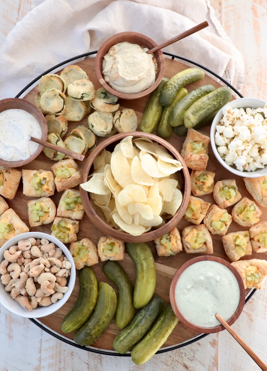 board filled with pickles, dips and snacks