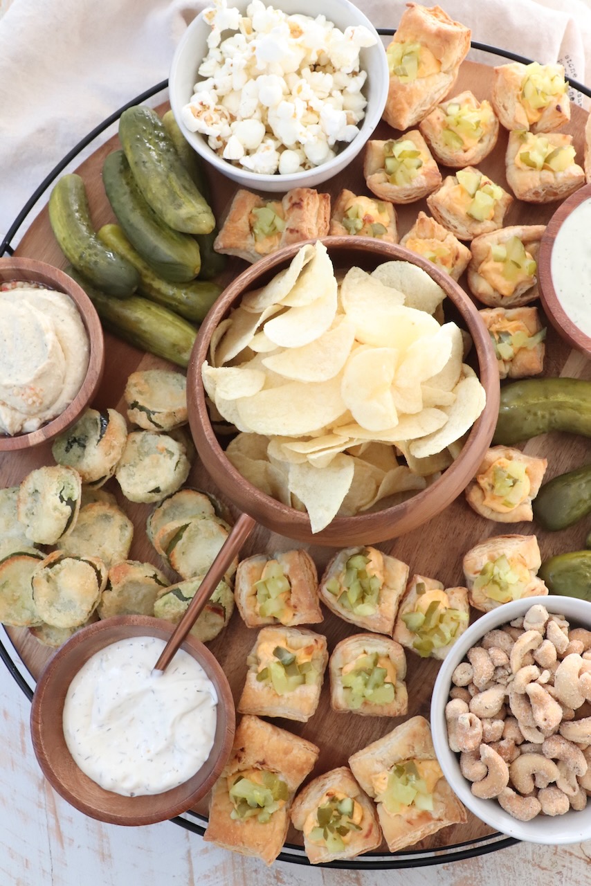 pickles and snacks on a large wood board