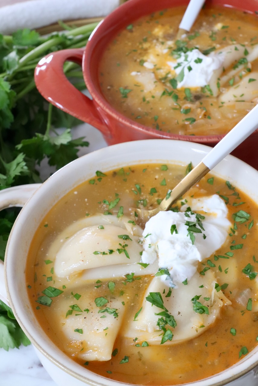 pierogi soup in bowls topped with sour cream and chopped parsley