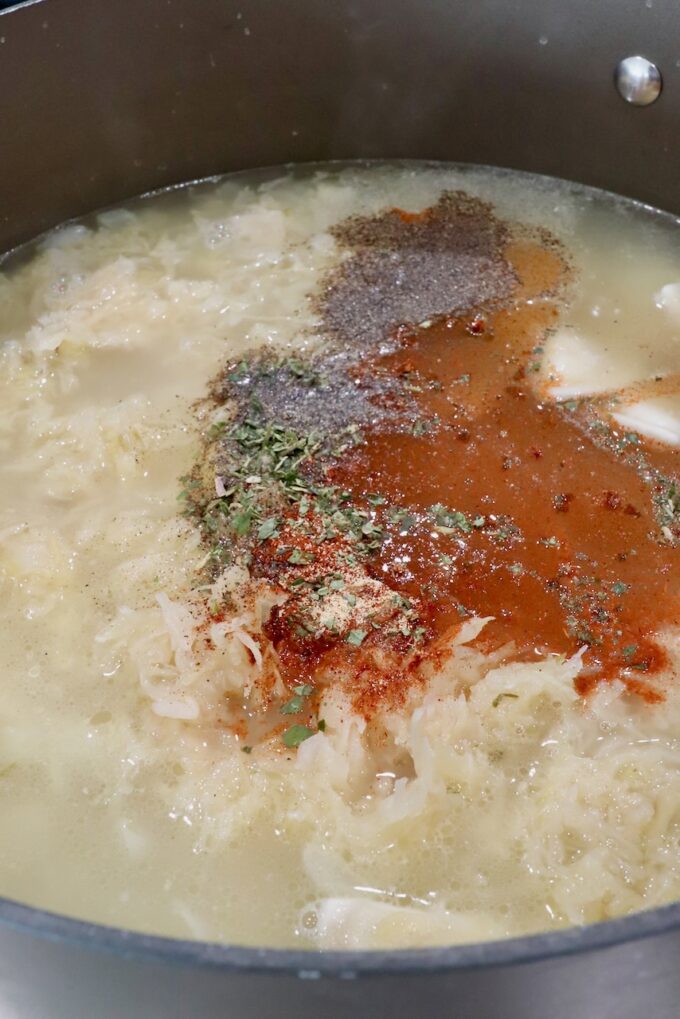 seasonings in a large pot of chicken broth and sauerkraut