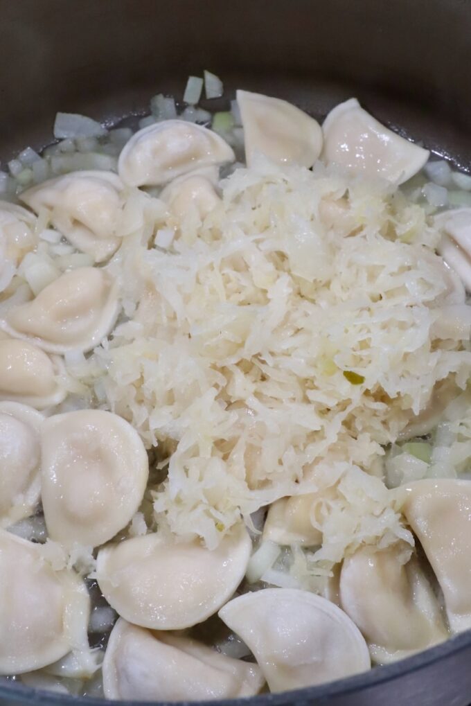 mini pierogis in a large pot with diced onions and sauerkraut