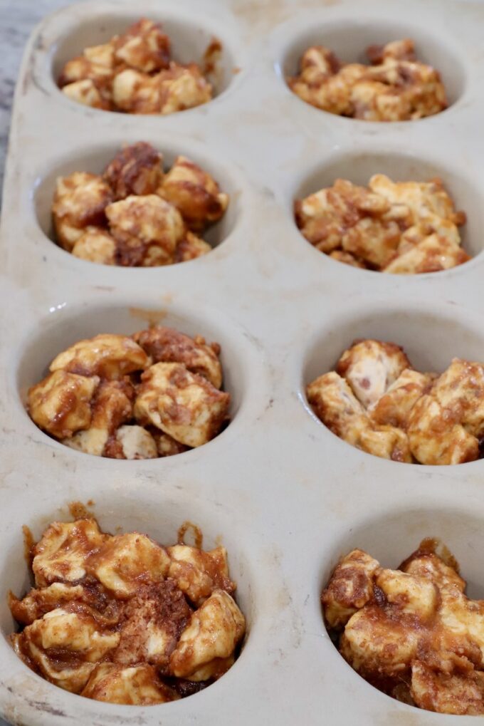 pieces of pumpkin coated cinnamon rolls divided into a muffin pan