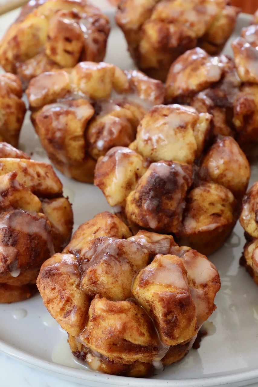 pull apart pumpkin cinnamon rolls on a plate drizzled with cream cheese icing