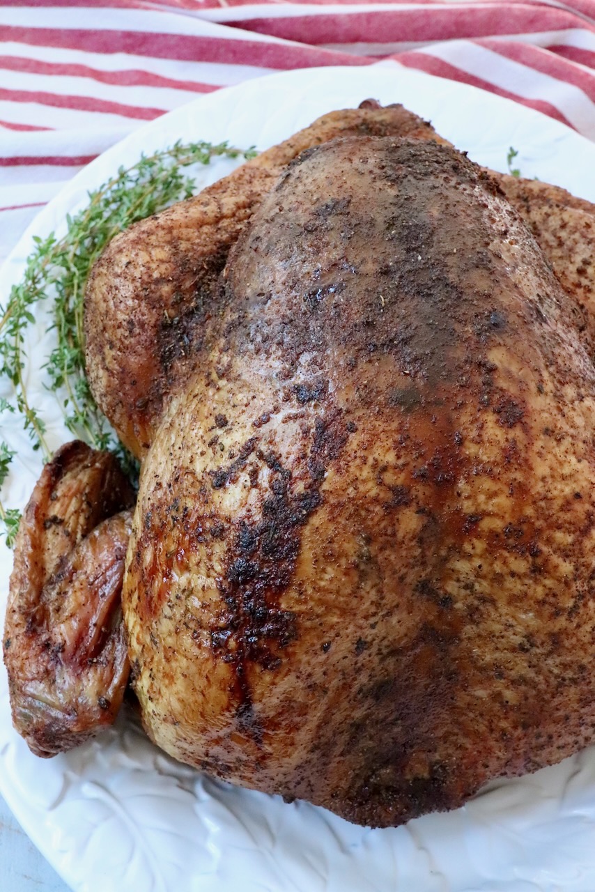 seasoned smoked turkey on a platter with fresh herbs