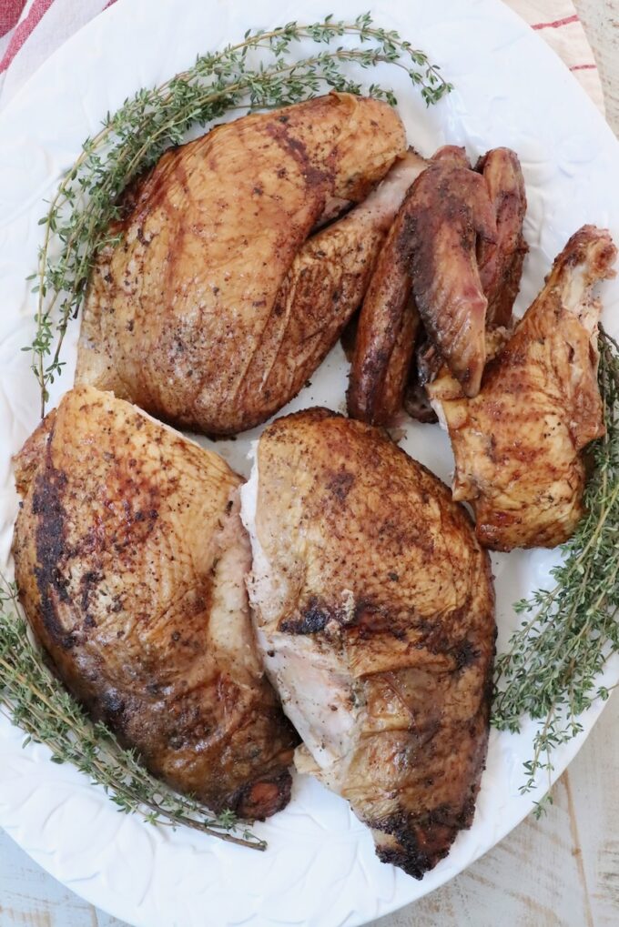 turkey thighs, drumsticks and wings on a platter with fresh herbs