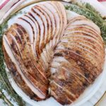 sliced smoked turkey on a plate with fresh herbs