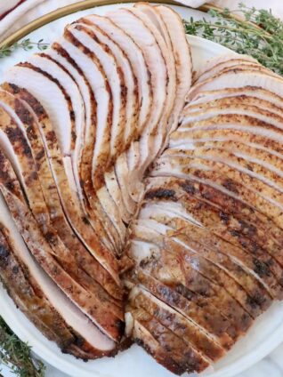 sliced smoked turkey on a plate with fresh herbs