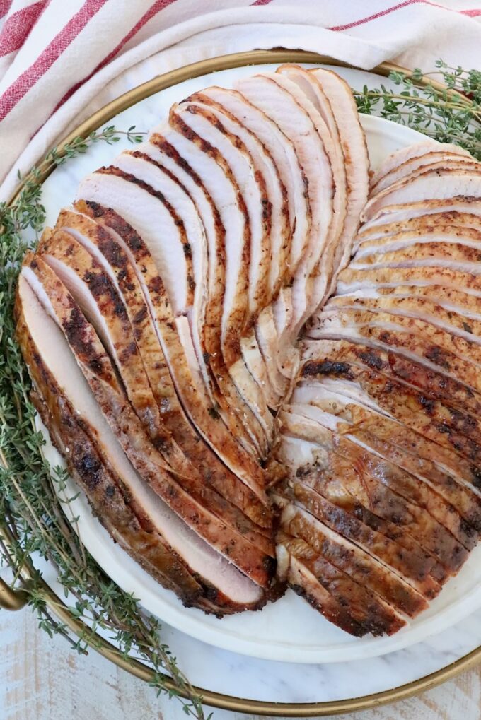 sliced turkey breast on a plate with fresh herbs