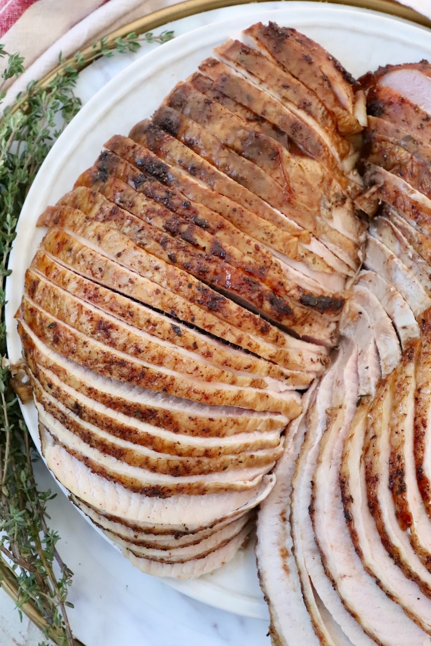 sliced turkey breast on a plate with fresh herbs