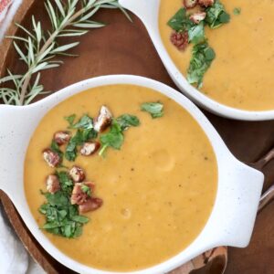 sweet potato soup in bowls topped with parsley and candied pecans