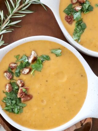 sweet potato soup in bowls topped with parsley and candied pecans