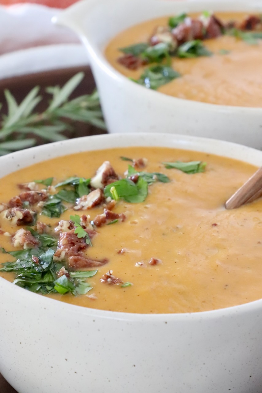 sweet potato soup in bowls topped with chopped parsley and nuts